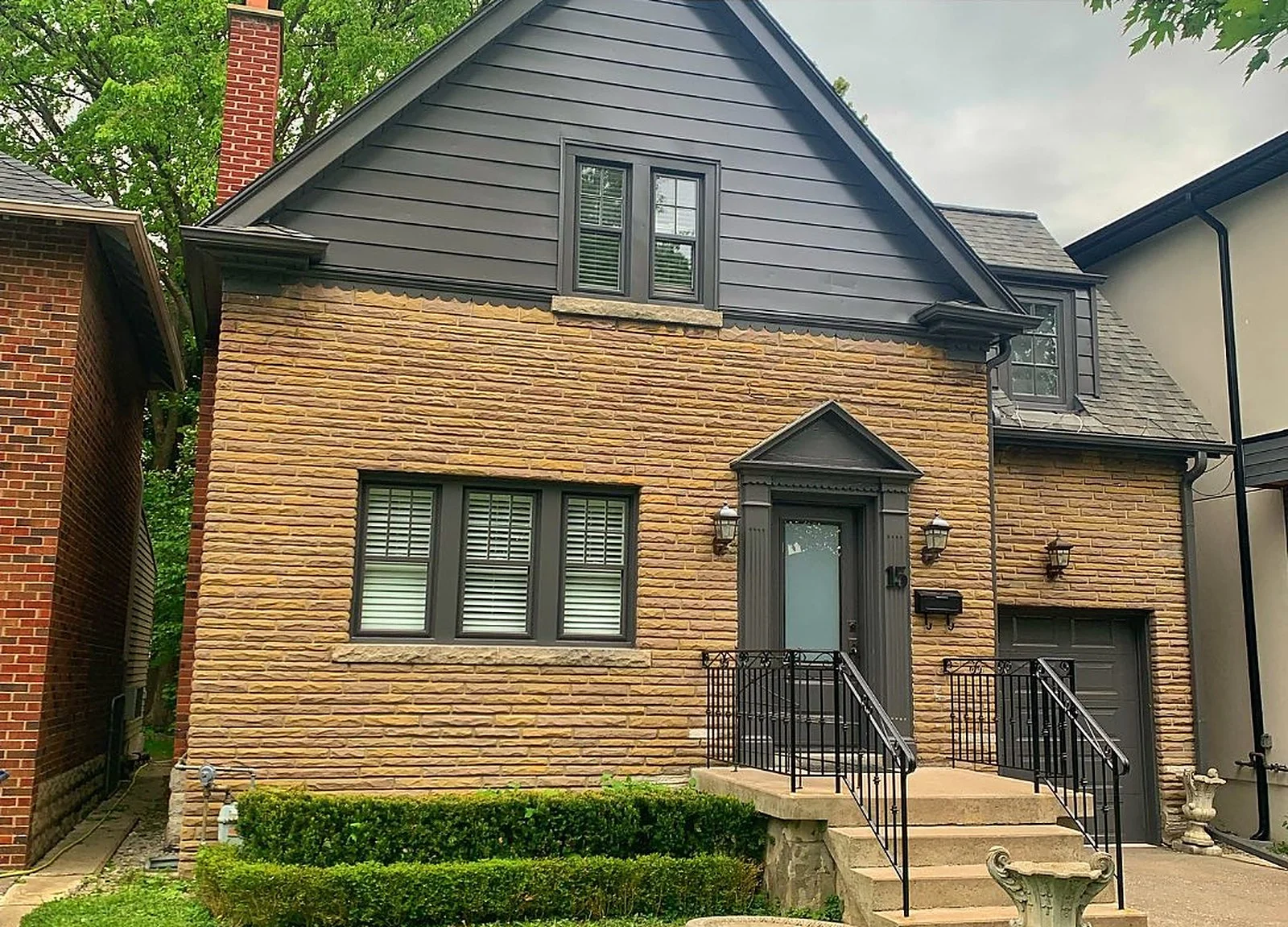 AFTER: Forest Hill house, siding painted dark grey, black trim, stone base