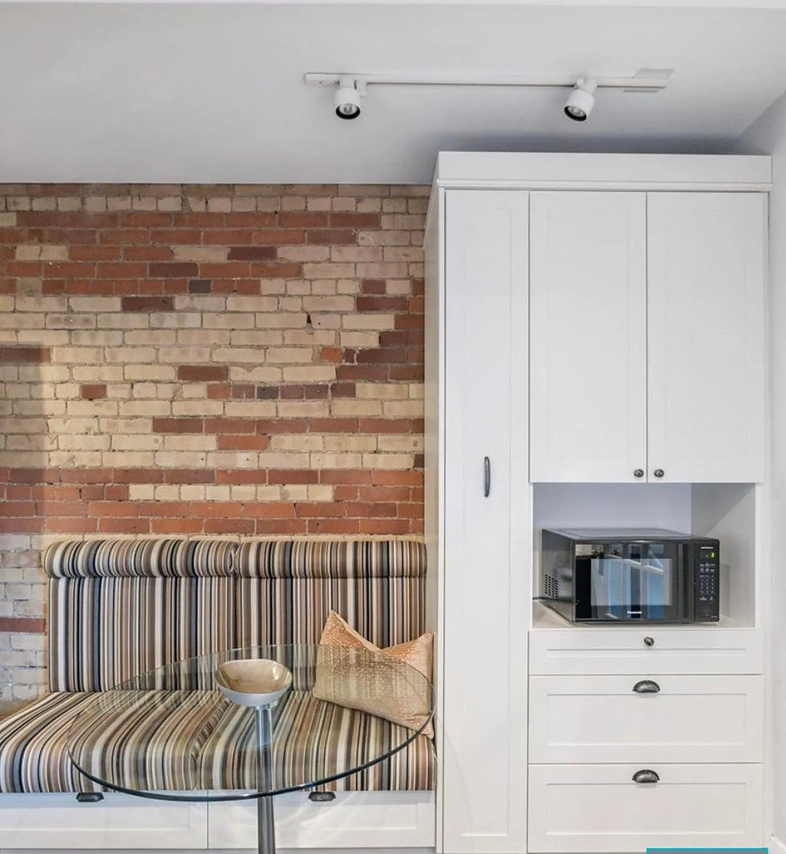Riverdale: breakfast banquette with exposed brick, white cabinets (Lome Irwin)