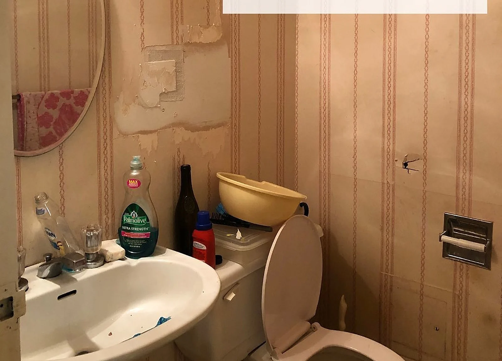 BEFORE: downtown condo bathroom with damaged striped wallpaper