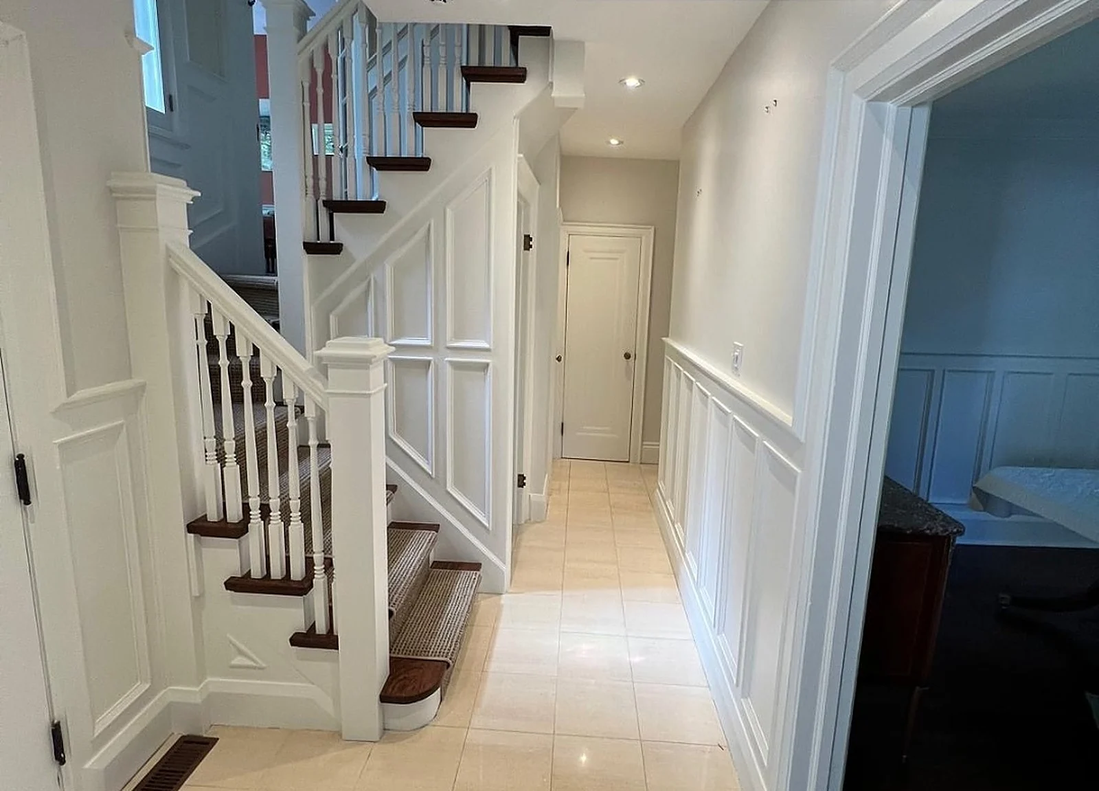 AFTER: hallway with white staircase and wainscoting, dark treads