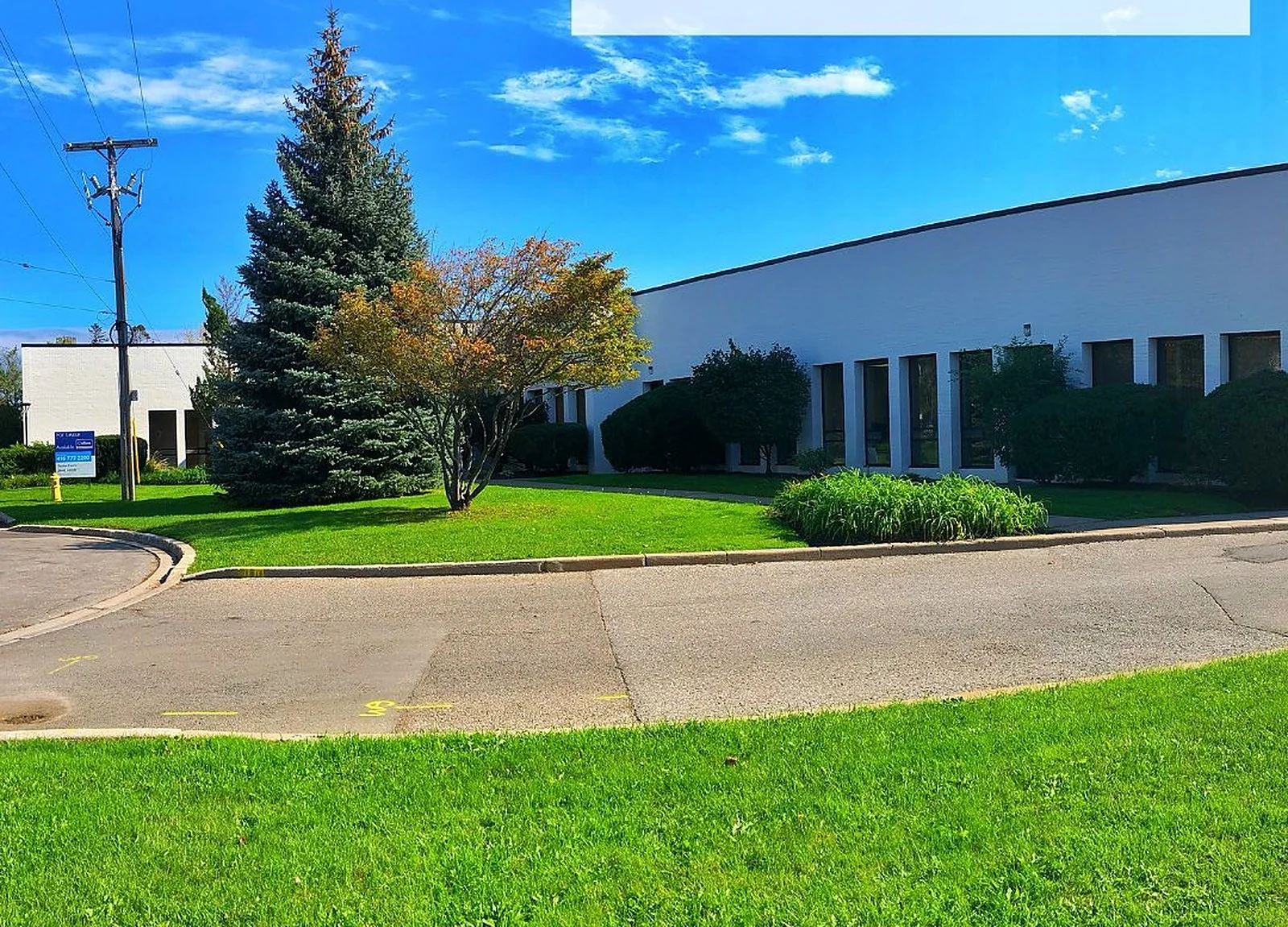 AFTER: same industrial building painted white/blue, blue sky