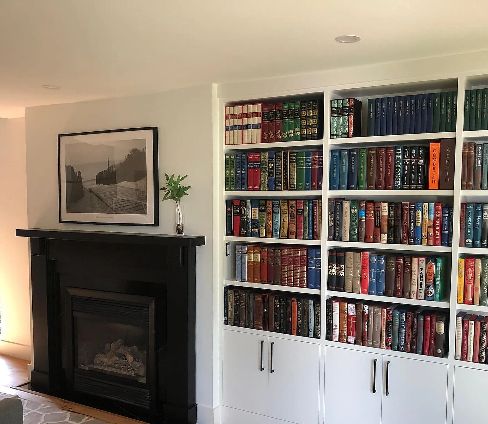 Library with white built-in bookshelves and black fireplace