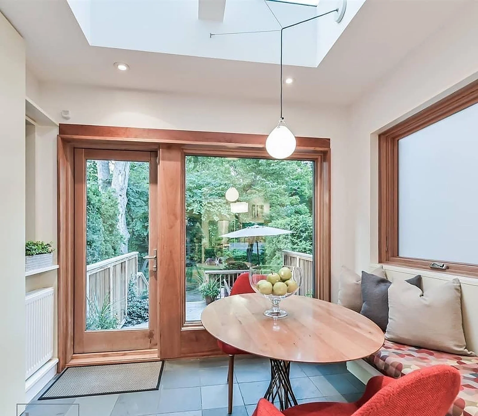 Summerhill breakfast nook with wood-framed windows, red chair, white walls