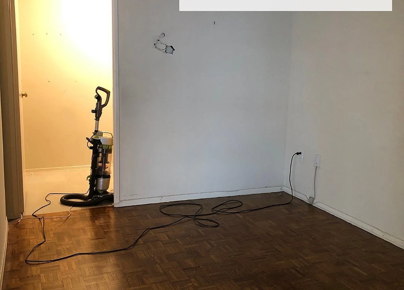 BEFORE: empty room with vacuum, drywall repairs