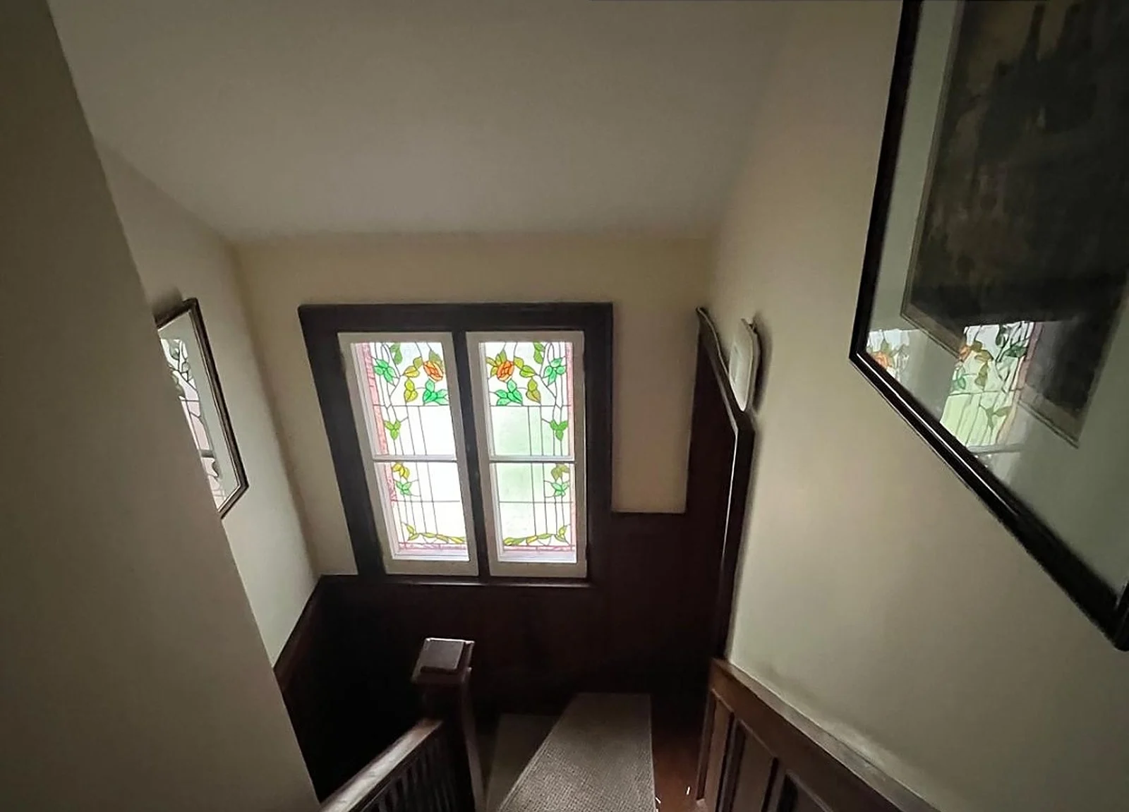 BEFORE: stair landing with stained-glass window, dark wood