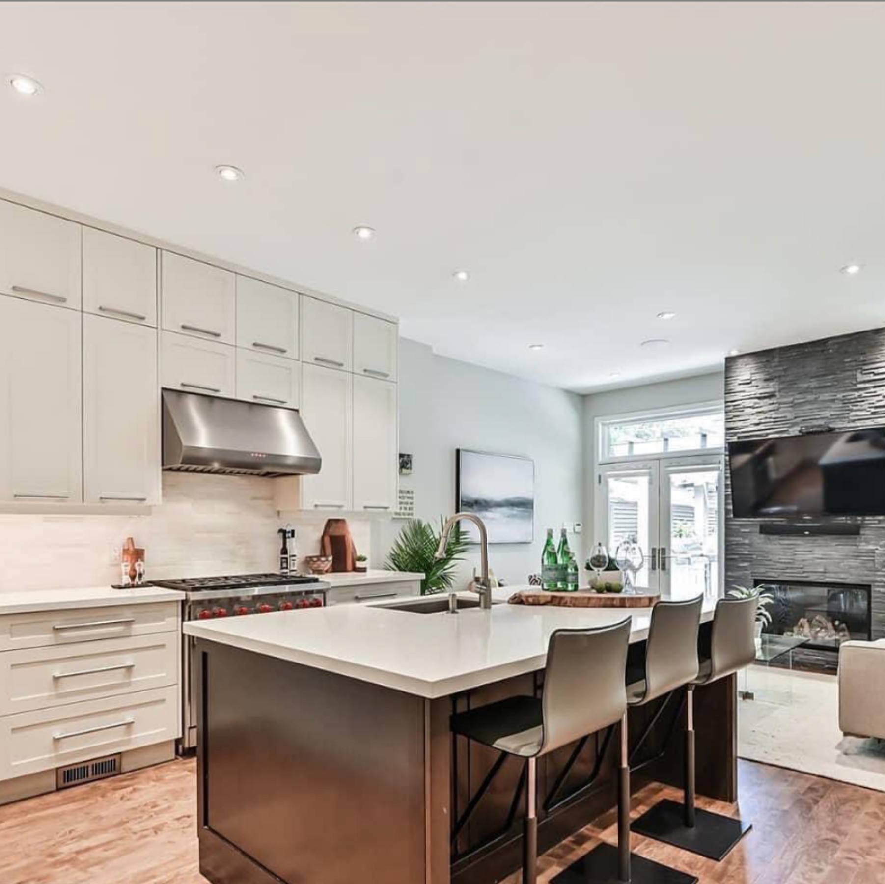 Bright white kitchen with a dark island and stone fireplace wall